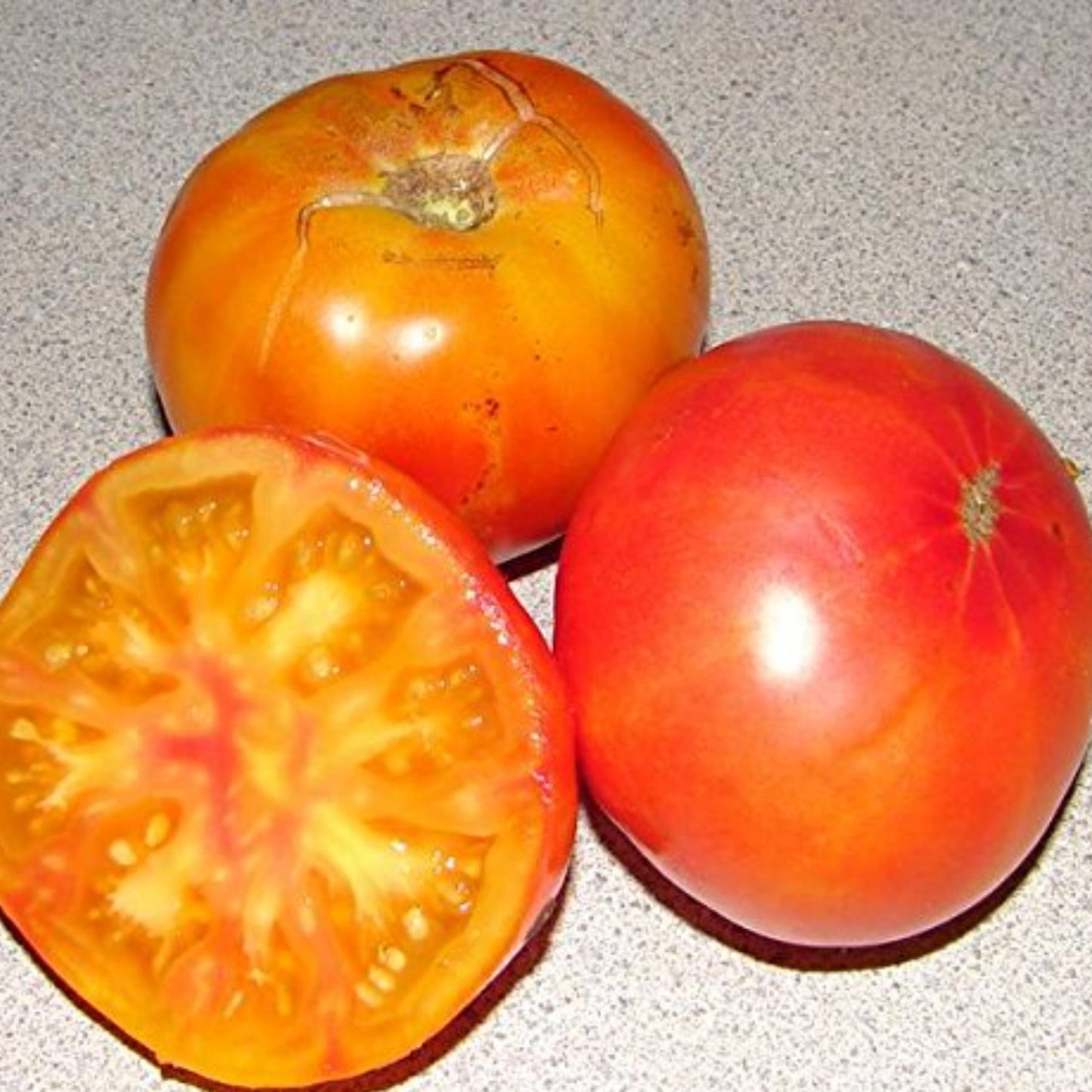 Two Whole Hillbilly Tomato and one sliced Deux tomates Hillbilly entières et une en tranches